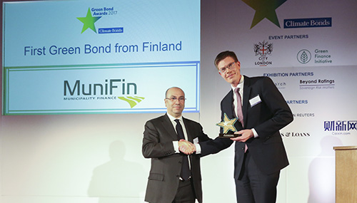Kuvituskuva, jossa oikealla seisova Kuntarahoituksen Antti Kontio vastaanottaa Climate Bonds Initiativen Green Bond Pioneer -palkinnon.