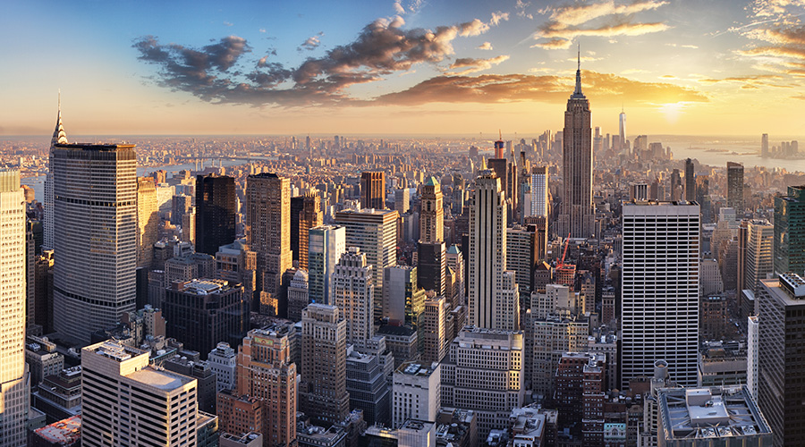 Kuvituskuva, jossa aurinko nousee New Yorkissa pilvenpiirtäjien takana.