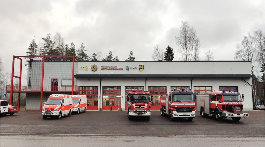 Kuvassa on pelastusasema, jonka edessä on paloautoja ja ambulansseja.